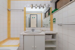 Een moderne badkamer met een wit wastafelmeubel, spiegel en betegelde wanden.