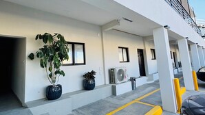 A modern building with a covered parking area, potted plants, and a car. - Capital O Hotel Jazuli, San Jose del Cabo (San José del Cabo)