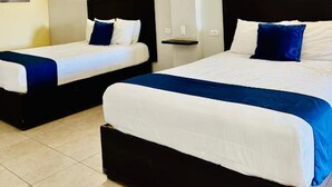 Two single beds with black headboards and white bedding, a small bedside table, and a wall-mounted light. - Capital O Hotel Jazuli, San Jose del Cabo (San José del Cabo)