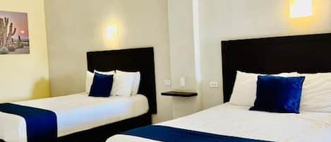 Two single beds with black headboards and white bedding, a small bedside table, and a wall-mounted light.