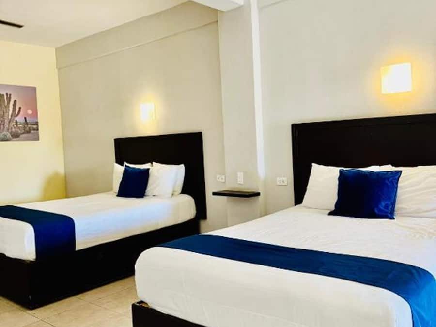 Two single beds with black headboards and white bedding, a small bedside table, and a wall-mounted light.