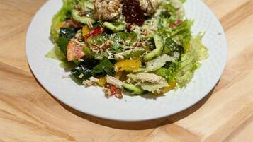 A plate of mixed greens salad with various vegetables and nuts on a white plate.