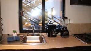 A kitchen with a stainless steel sink, a coffee maker, and a blender on the counter. - Capital O Hotel Jazuli, San Jose del Cabo (San José del Cabo)