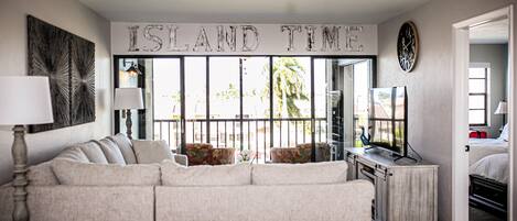 A living room with a large sofa, a TV, and a sign that reads "ISLAND TIME".