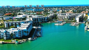 A marina with boats docked, surrounded by multi-story buildings with balconies and a view of the ocean. - ANGLERS COVE - WELCOME TO "ISLAND TIME" AT MARCO ISLAND (Marco Island)