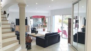 A spacious living area with a staircase, a black sofa, a coffee table, and a large window. - VILLA ANDALUCIA, Air-conditioned, Heated pool, Sea view of calanques. Sleeps 6 (La Ciotat)