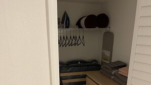 Une chambre à coucher de taille modeste, comprenant un lit, une commode et une petite étagère où sont rangés des objets personnels.