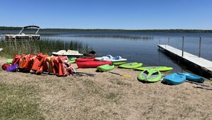 Um cais à beira do lago com caiaques e coletes salva-vidas.