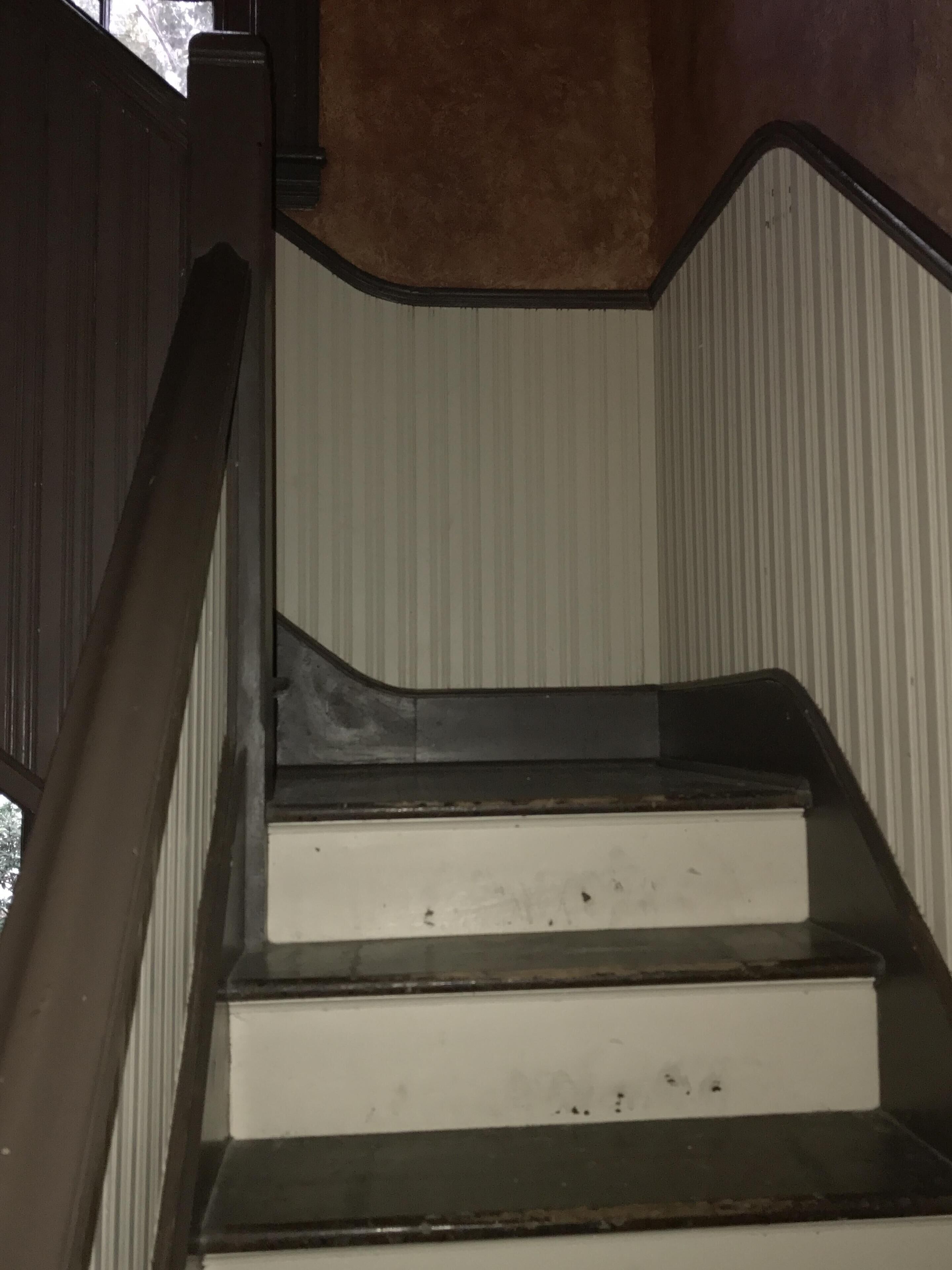 Un escalier avec des rampes en bois et des marches blanches.