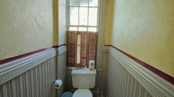 Un baño pequeño con un inodoro, dos cubetas y una ventana.