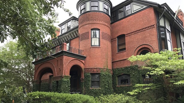 A historic building with a brick facade, arched windows, and a turret. - George Baldwin House Suite (Savannah)