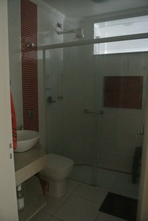 Une salle de bain avec une douche à parois de verre, un lavabo blanc et des toilettes.