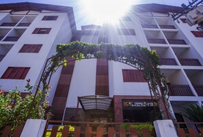 Un immeuble à plusieurs étages doté d’une entrée centrale, d’une galerie couverte et d’une enseigne indiquant un restaurant appelé « Comida Maria & Jose Pirani ».