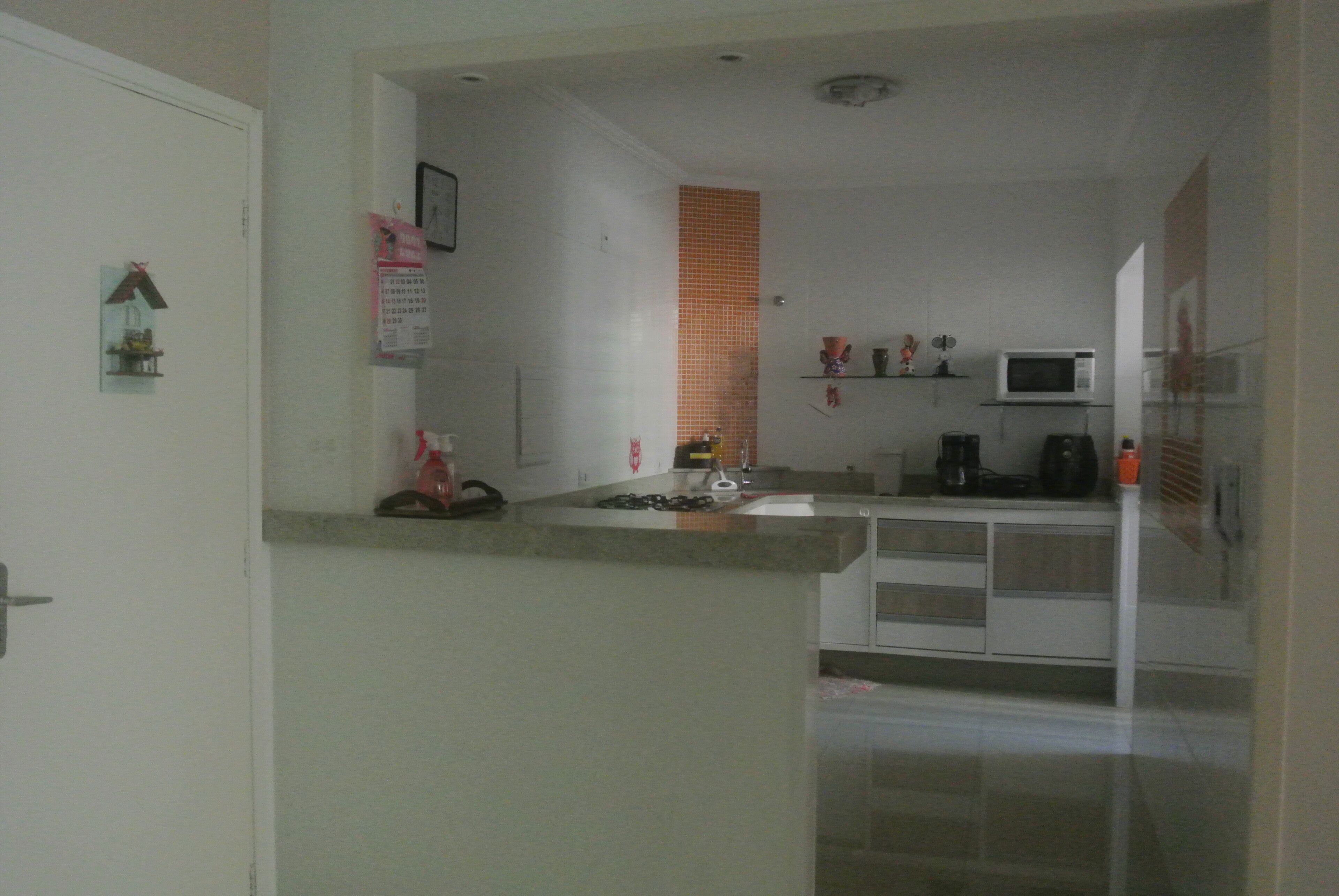 A compact kitchen with a microwave, coffee maker, and a small shelf.