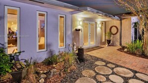 Una casa moderna con un patio, ventanas amplias y un jardín cuidado.