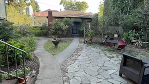 Une terrasse dallée de pierres, avec un chemin sinueux menant à une maison.