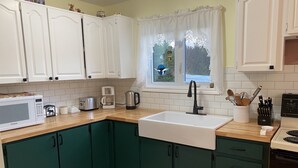 Una cocina con armarios blancos, un lavabo, una cafetera y un microondas.