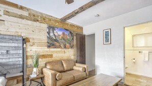 Ein Wohnzimmer mit Holzwand, einer Couch, einem Couchtisch und einem Gemälde einer Berglandschaft.