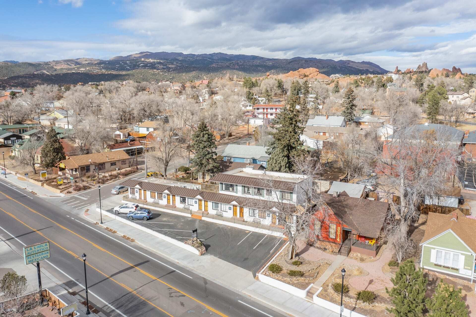 A street view of a town with buildings, a road, and mountains in the background.