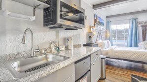 Una cocina moderna con encimera de granito, pileta de acero inoxidable y microondas integrado.