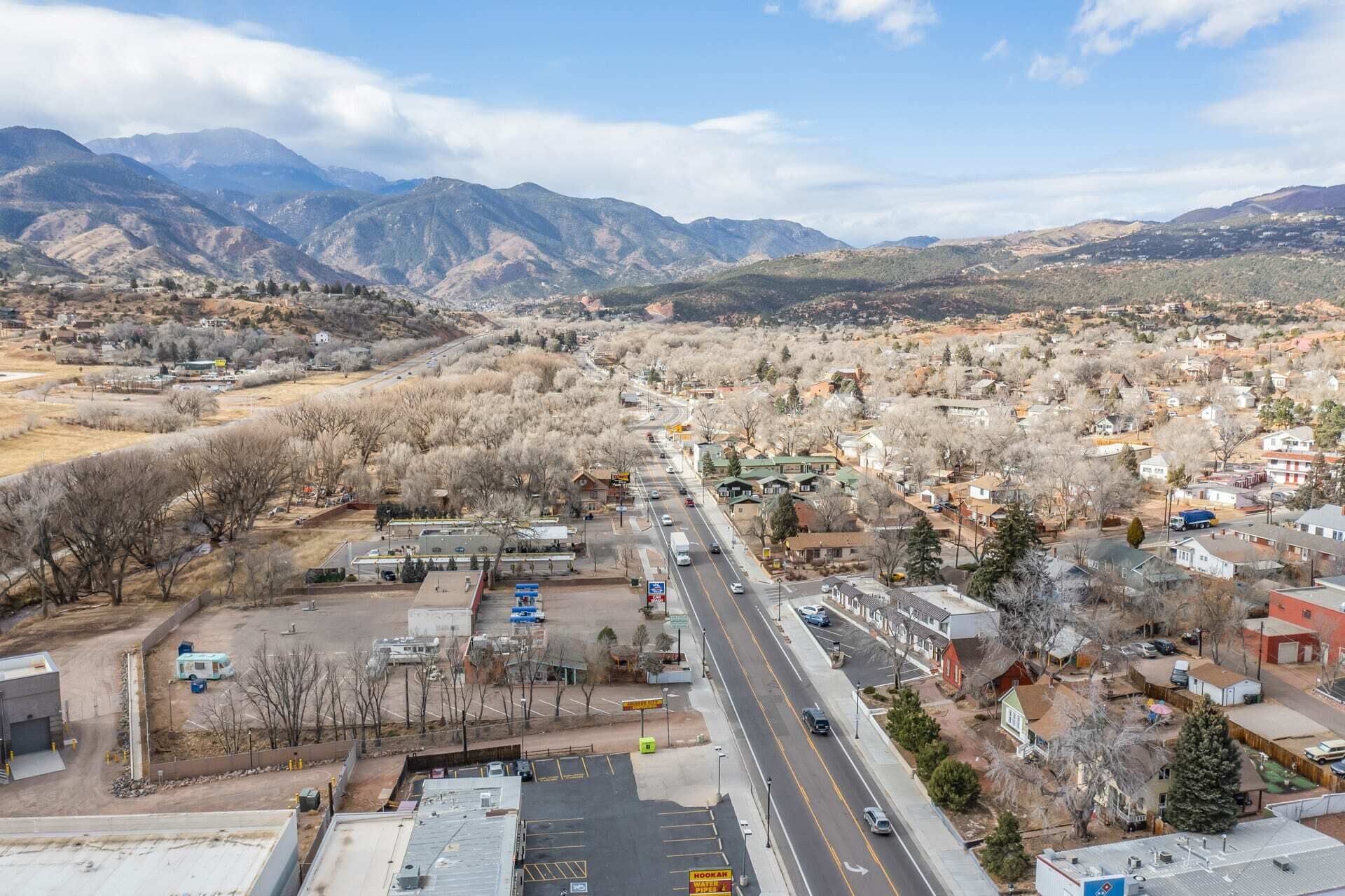 Un pueblo con una calle principal, edificios y montañas al fondo.