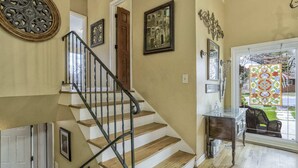 Una escalera con peldaños de madera y barandillas de metal que conduce a una puerta.