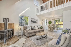 Un salon spacieux doté d’une cheminée, d’un plafond haut et d’un balcon.