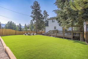 Ein Garten mit gepflegtem Rasen, einer Holzterrasse und einer Terrasse mit Gartenmöbeln.