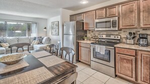 A modern kitchen with stainless steel appliances, wooden cabinets, and a dining area with a table set for four.