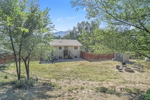 A single-story house with a fenced yard, a patio with outdoor furniture, and a clear view of the surrounding landscape.