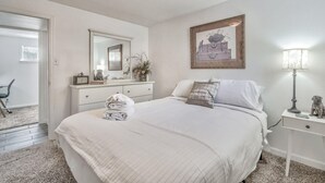 A bedroom with a bed, a dresser, a mirror, a lamp, and a painting on the wall.