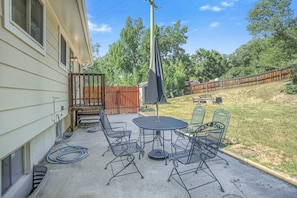 A patio with a round table and four chairs, a covered umbrella, and a wooden fence in the background. - 4brnear Garden Of The Gods With Large Yard (Colorado Springs)