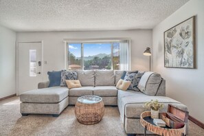 Relax in this inviting living space with a large sofa, round coffee table, and a beautiful view of the outdoors.