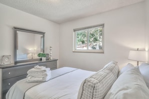 A bedroom with a bed, a dresser, a mirror, a window, and a lamp. - 4brnear Garden Of The Gods With Large Yard (Colorado Springs)