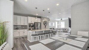 A modern kitchen with white cabinets, stainless steel appliances, and a central island with bar stools. - 3BD Rooftop Lounge Restaurants & Parks (Castle Rock)