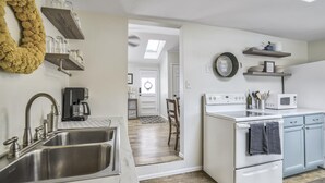 A modern kitchen with a double sink, a coffee maker, a microwave, and a stove. There is a wooden wreath on the wall and a clock above the stove. - 3bd1 Mile to Garden of the Godstraveler's Home (Colorado Springs)