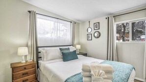 A neatly arranged bedroom with a bed, bedside tables, and a window with curtains. - 3bd1 Mile to Garden of the Godstraveler's Home (Colorado Springs)