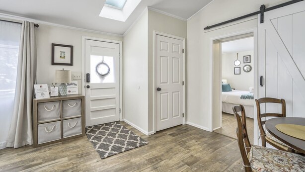 A modern, well-lit room with a skylight, a wooden floor, a door with a circular window, and a dining area with a table and chairs. - 3bd1 Mile to Garden of the Godstraveler's Home (Colorado Springs)