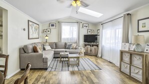 A living room with a grey sofa, a coffee table, a TV, and a ceiling fan. - 3bd1 Mile to Garden of the Godstraveler's Home (Colorado Springs)