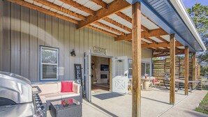 Un espace extérieur abrité avec des sièges, un barbecue, un panneau d’accueil et une enseigne indiquant « Quartier des cow-boys ».