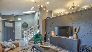 Una sala de estar moderna con sofá, mesa de centro, televisor y elementos decorativos.