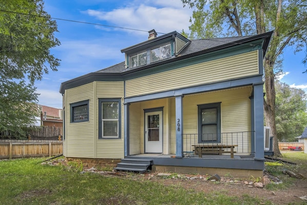 A two-story house with a front porch, a chimney, and a small deck.