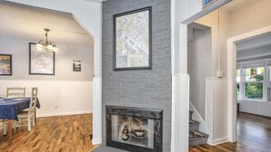 A dining area with a wooden table and chairs, a fireplace with a stone surround, and a staircase leading to another room. - 3bdcheyenne Mtn Suburbsrestaurants & Hiking (Colorado Springs)