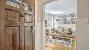 A wooden door with a glass panel, a living room with a sofa, a coffee table, and a wall decorated with pictures. - 3bdcheyenne Mtn Suburbsrestaurants & Hiking (Colorado Springs)