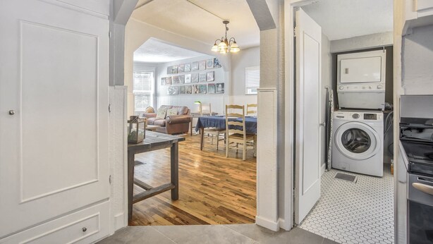 A laundry room with a washing machine and dryer, a dining area with a table and chairs, and a living room with a sofa and a chandelier. - 3bdcheyenne Mtn Suburbsrestaurants & Hiking (Colorado Springs)