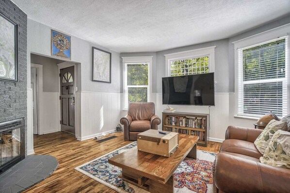 Ein Wohnzimmer mit Kamin, Fernseher, Ledermöbeln und einer Bücherwand.