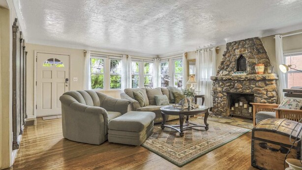 A cozy living room with a stone fireplace, a large sofa, and a coffee table. - 2BR Manitou Get Away Close To Everything! (Manitou Springs)