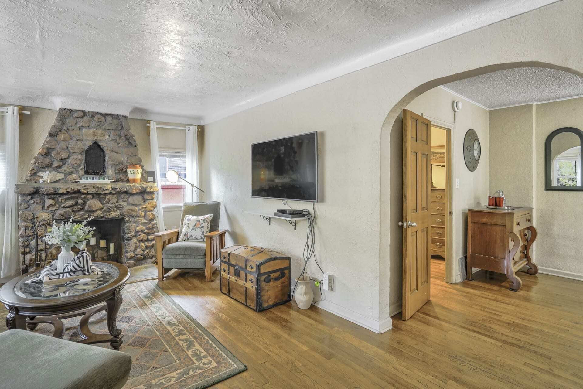 A living room with a stone fireplace, a television, and a wooden cabinet.