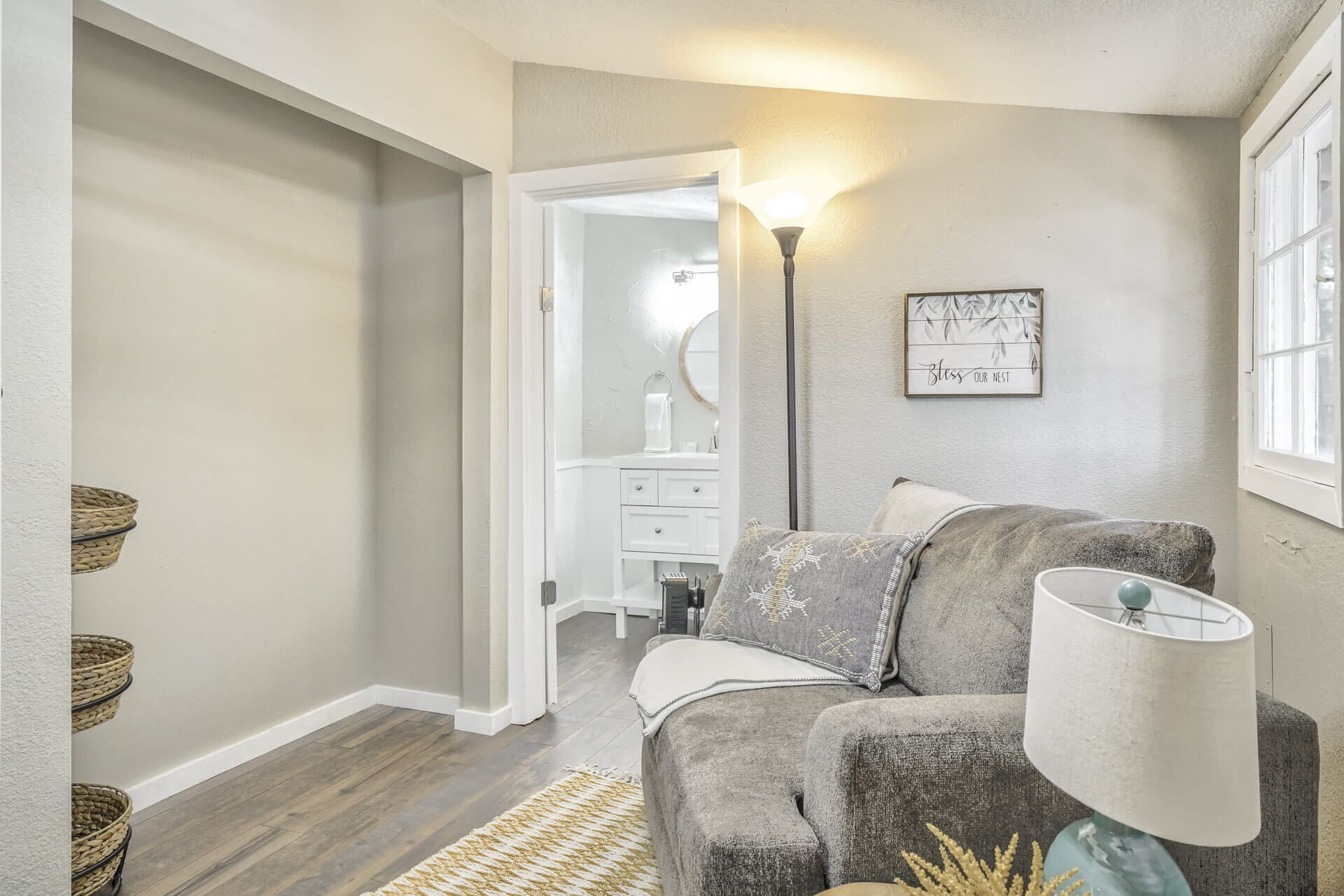 A cozy living room with a grey sofa, a floor lamp, and a wall-mounted picture frame.