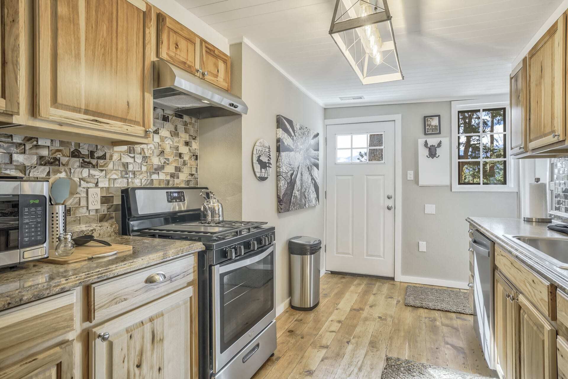 A kitchen with wooden cabinets, a stainless steel range, a microwave, and a large window.